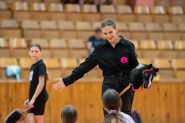 Hobby Horsing-demonstratie in een sporthal met een vrouw die een zwart Hobby Horse vasthoudt