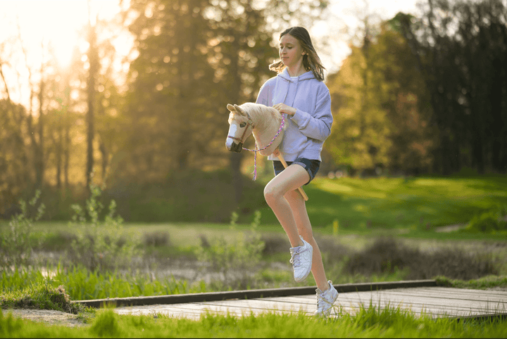 Girl enjoying Hobby Horsing outdoors with a white Hobby Horse at sunset