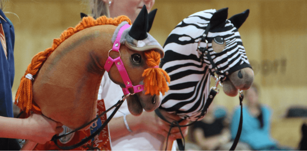 Twee Hobby Horses met gevlochten manen, één bruin met oranje garen en één met zebrapatroon