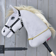 Een grijze Hobby Horse LarDen met zwart hoofdstel, gouden manen en handgemaakte Cordéo Nature hangt aan een houten stok tegen een grijze muur. Een geel polypropyleentouw is om de hals gelust.