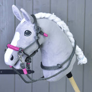 A plush gray and white hobby horse with a braided mane and black eyes models the Hobby Horse LarDen Rope set Grey (size M) in front of wooden paneling, highlighting unique handmade riding gear.