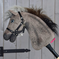 Hobby Horse Bolero met zwart halster - maat S van Hobby Horse LarDen met een pluchen hengstenhoofd met realistische manen, gemonteerd op een stok en afgebeeld tegen een lichtgrijze houten wand.
