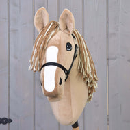 The Hobby Horse LarDen Hobby Horse Bren with Black Halter, featuring a tan plush body, white blaze, and cream-and-brown yarn mane, stands against a light wooden background.