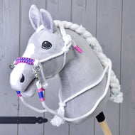 Touwset wit (maat M) van Hobby Horse LarDen met een grijze pluchen Hobby Horse met witte manen, teugels en een gevlochten halster voor Hobby Horse met roze en blauwe accenten, weergegeven tegen een houten achtergrond.