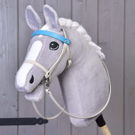 Aqua kunstleer set - hoofdstel, teugels en martingaal van Hobby Horse LarDen op een pluche grijze Hobby Horse met expressieve ogen en witte manen, gemonteerd op een houten stok tegen een achtergrond van lichtgrijze houten planken.