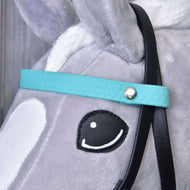 Close-up van een grijs pluchen paardenhoofd van Hobby Horse LarDen met een turquoise Compleet hoofdstel zonder neusriem. Kenmerken zijn een zwarte teugel, wit oor, witte aftekeningen op het gezicht en een oog in cartoonstijl met zwarte omlijning en witte highlight.