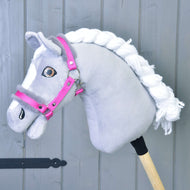 Halster roze met bont van Hobby Horse LarDen op een grijze Hobby Horse met witte manen van garen, witte aftekeningen op het gezicht en gemonteerd op een houten stok tegen een grijze houten achtergrond.