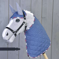 The Set Jeans hobby horse by Hobby Horse LarDen features a gray horse with a blue quilted blanket and matching ear bonnet trimmed in plaid, all mounted on a wooden stick against a gray wooden background.