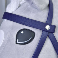Close-up van het gezicht van een pluchen paard met een gestikt zwart-wit oog, met het Compleet hoofdstel met neusriem Donker Paars van Hobby Horse LarDen; het hoofdstel heeft een zilverkleurig knoopdetail en de vacht van het paard is lichtgrijs.