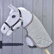 Een grijze pluchen Hobby Horse van Hobby Horse LarDen met een zwart hoofdstel en Deken Silver Eleganza staat tegen een houten wand met verticale panelen.