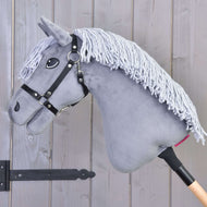 Hobby Horse Grace met Zwart Halster van Hobby Horse LarDen is een grijze Dutch Warmblood met manen van garen, gemonteerd op een houten stok en getoond tegen een wand van houten panelen.