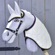 Set Leonardo van Hobby Horse LarDen met een grijs pluchen Hobby Horse, witte gewatteerde deken, bijpassend oornetje, zwart hoofdstel en teugels op een houten stok, afgebeeld tegen een grijze houten wand.