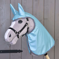 Grijze Hobby Horse van Hobby Horse LarDen met een zwart hoofdstel, grote vilten ogen en een Regenjas Lichtblauw-kap met bijpassende oren, afgebeeld voor een houten wand.