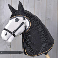 Realistische Hobby Horse met wit gezicht, zwarte manen en zwart hoofdstel tegen een achtergrond van licht houten panelen, met Regenjas Luxury van Hobby Horse LarDen.