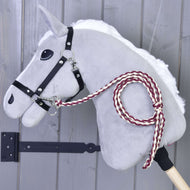 Hobby Horse - Gebreid Leidsnoer Maroon van Hobby Horse LarDen, met een grijs vilten hoofd met een zwart hoofdstel en handgebreid kastanjebruin-wit leidsnoer, gemonteerd op een houten stok tegen een grijze houten wand.