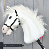 Hobby Horse Nexus met zwart halster van Hobby Horse LarDen, een witte pluche sportpaard met pluizige manen, groot knoopoog en zwart halster—perfect voor elke liefhebber. Gefotografeerd tegen een grijze houten wand.