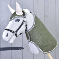 Set Olivetti van Hobby Horse LarDen, een grijze hobby horse met een groene gewatteerde deken en hoofdstel, zwart halster, witte oren en stijlvolle accessoires, getoond tegen een lichtgrijze houten wand.