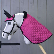 A plush hobby horse by Hobby Horse LarDen stands on a wooden stick, featuring a white face, black bridle, and wearing the Set Thermo Pink blanket and ear bonnet in front of a gray wall—a charming equestrian decoration.