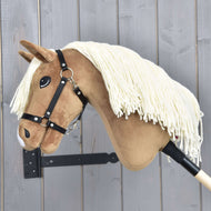 Hobby Horse Smart met zwart halster van Hobby Horse LarDen, met crèmekleurige garenmanen en een houten stok, is getoond op een houten wand met verticale grijze panelen.
