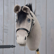 Hobby Horse Thor met zwart halster van Hobby Horse LarDen, met een zachte grijze kop, zwarte manen en tuig op een houten stok, tegen een achtergrond van lichte houten panelen.