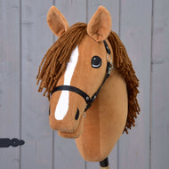Hobby Horse Wendy met Zwart Halster van Hobby Horse LarDen heeft een bruin pluchen hoofd, gevlochten bruine manen van garen, witte streep op de snuit en zwart halster voor Hobby Horse, geïnspireerd op een vosmerrie en getoond tegen een grijs houten achtergrond.