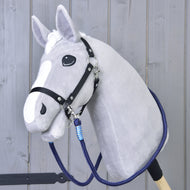 The Hobby Horse LarDen Reins Blues is a gray plush hobby horse with a black bridle, handmade reins, blue lead rope, and white face markings on a wooden stick, shown in front of a gray wooden wall.