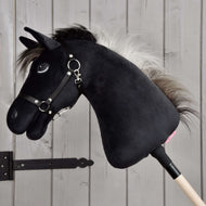 Hobby Horse Bond met zwart halster van Hobby Horse LarDen, een zwarte pluchen Hobby Horse met witte manen, zwart halster en teugels op een houten stok, getoond voor een licht houten wand, perfect voor elke Hobby Horse Bond-fan.