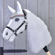 Close-up van een grijze pluche hobby horse van Hobby Horse LarDen, getoond met een hoofdstel, decoratieve frontriem en het Oornetje Silver Eleganza voor insectenbescherming, tegen een houten omheining.