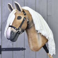 Hobby Horse Connie met Zwart Halster van Hobby Horse LarDen heeft een realistisch lichtbruine kop, witte bles, zwart halster en lange witte manen van garen op een houten stok, weergegeven tegen een grijze houten wand.