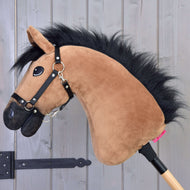Hobby Horse Cookie met Zwart Halster van Hobby Horse LarDen, met een pluchen lichtbruine snoet, zwarte manen en zwart halster op een houten stok, ideaal als keuze voor liefhebbers van springen, getoond tegen een grijze houten achtergrond.