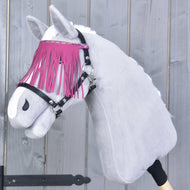 Hobby Horse LarDen draagt Halster zwart met roze franjes en staat voor een grijze houten achtergrond, met een witte vacht en een stijlvolle frontriem met roze franjes.