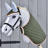 Set Moos van Hobby Horse LarDen met een grijs Hobby Horse met zwart hoofdstel, groene gewatteerde deken en lichtblauw oornetje op een houten stok, weergegeven tegen een grijze houten wand.