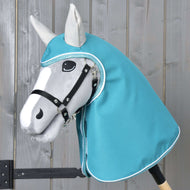 Regenjas Turquoise van Hobby Horse LarDen is een grijze Hobby Horse met een zwart hoofdstel en een turquoise regenjaskap, met een realistisch gevormd gezicht met zwarte en witte details, tegen een lichte houten achtergrond.
