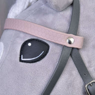 Close-up van Compleet kunstleren hoofdstel grijs met roze hoofdband van Hobby Horse LarDen op een pluchen speelgoedpaard, met een zwart gestikt oog en gedetailleerde riemen bevestigd met een metalen klinknagel.