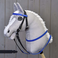 Pluche hobby horse van Hobby Horse LarDen met een grijs gezicht, witte manen en blauwe rubberen teugels, gemonteerd op een houten stok en geplaatst voor een achtergrond van houten panelen.