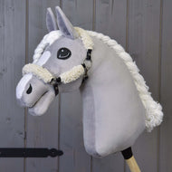 Hobby Horse LarDen met een pluche grijze hobby horse met een zwart halster met volledige vacht en kunstleren accenten, gemonteerd op een houten stok tegen een achtergrond van houten planken.