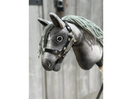 A close-up of the Hobby Horse LarDen "Little Prince" (size XS), featuring a grey fabric head, black halter, button eyes, and yarn mane against a blurred wooden background.