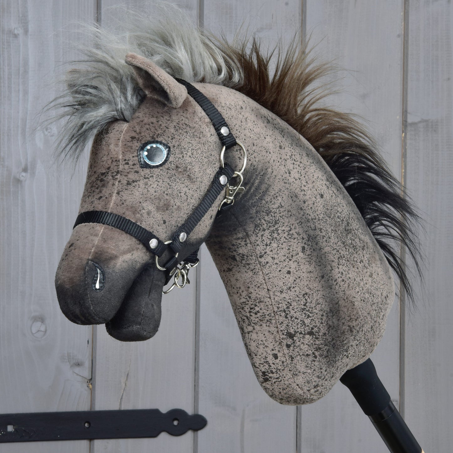 The Hobby Horse Bolero with Black Halter (size S) by Hobby Horse LarDen features a brown-speckled Appaloosa head, black halter, button eyes, and a fluffy multi-toned mane. Photographed against a wooden background.