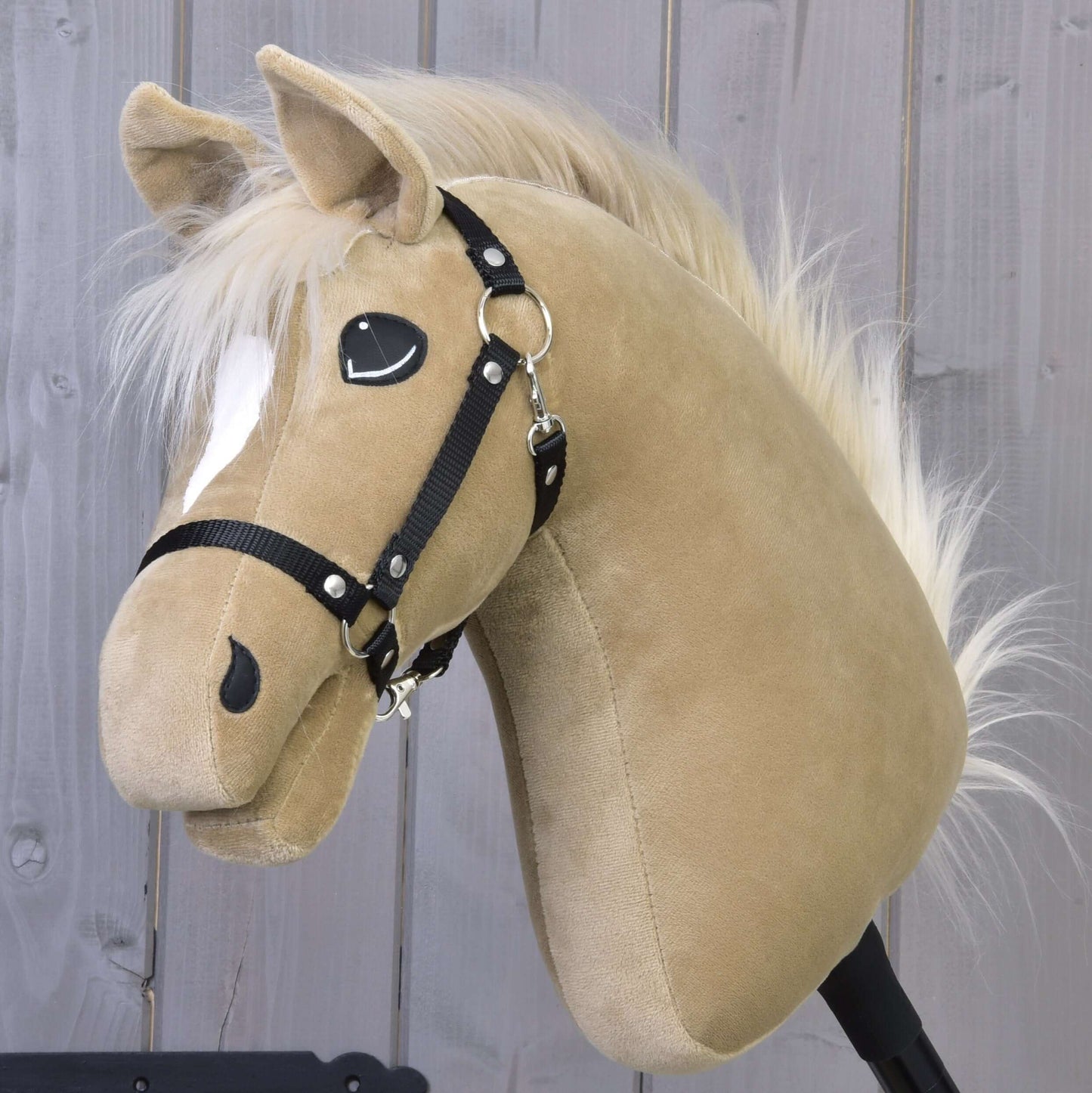 The Hobby Horse LarDen "Hobby Horse Dancing Lady with Black Halter," a beige plush mare with white mane and forehead patch, stands in front of a wooden plank wall.