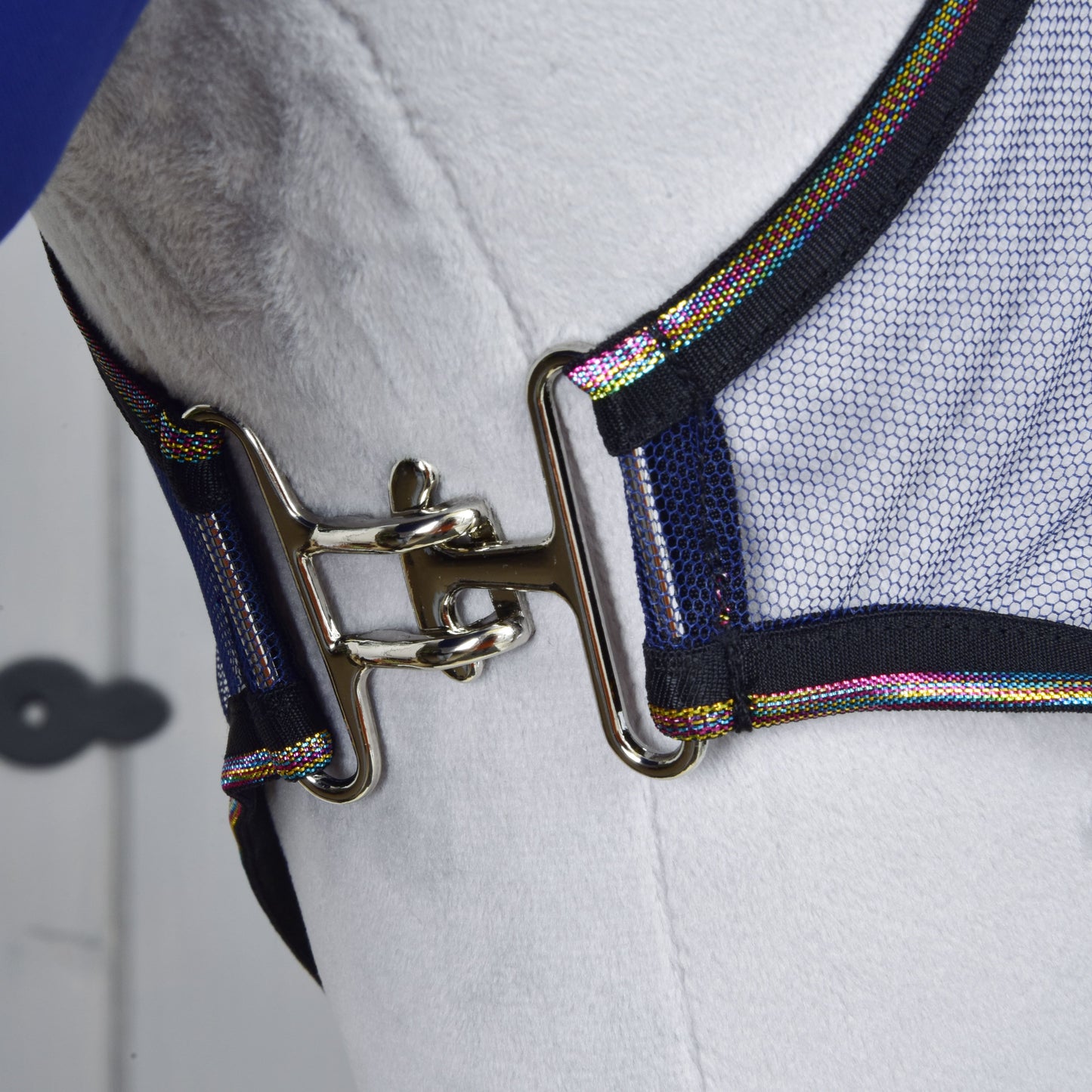 Close-up van een glanzende metalen gesp die een mesh riem met kleurrijke rand vastmaakt, onderdeel van de Set Vlieg Combo van Hobby Horse LarDen, weergegeven op een wit oppervlak.