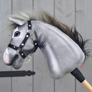 Side view of the grey Hobby Horse with a white blaze, pink muzzle and black halter on a wooden stick