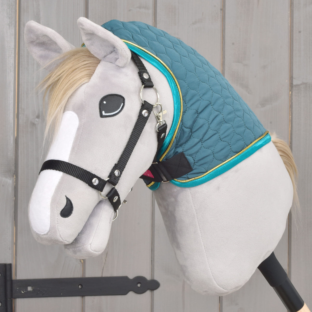 Green quilted Hobby Horse blanket with removable neck cover shown from the side on a grey Hobby Horse