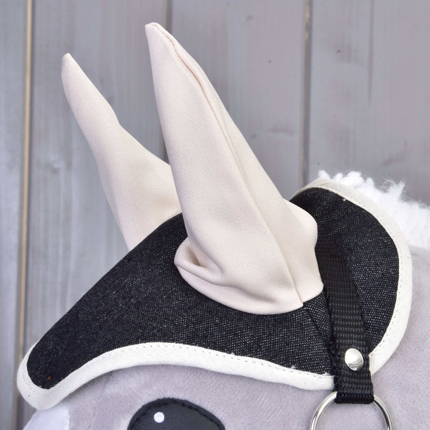 Close-up van de grijs pluchen Set Blue Denim Hobby Horse van Hobby Horse LarDen met een zwart-wit stoffen hoofdstel en zachte crèmekleurige oren, als decoratie voor elke fan.