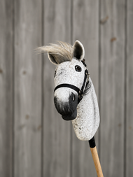 Hobby Horse Luna met Zwart Halster - maat S van Hobby Horse LarDen, met een grijze pluchen Appaloosa-kop, zwart halster en handvat van houten stok, getoond tegen een achtergrond van grijze houten planken.