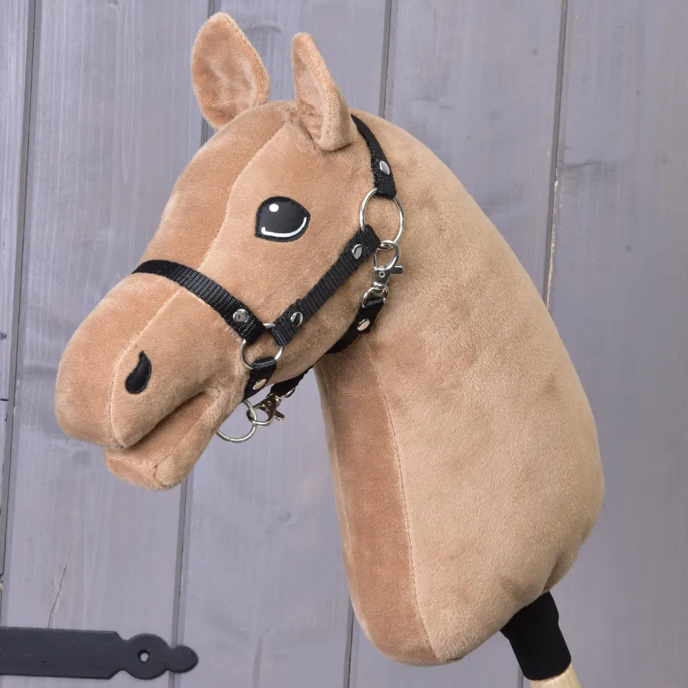 A caramel hobby horse with a black harness stands before a wooden wall, showcasing the “Build your horse” by related_to_12441055625556—an invitation to personalize your own unique and playful hobby horse.