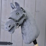 Introducing Build your horse by related_to_12441055625556: a custom hobby horse with a dark grey plush head, light grey mane, and black harness, mounted on a wooden stick and displayed against a wooden panel background.