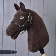 The Build your horse by related_to_12441055625556 features a dark brown custom hobby horse head with chocolate yarn, black bridle, white eye, upright ears, and is mounted on a wooden stick against a gray wooden background.