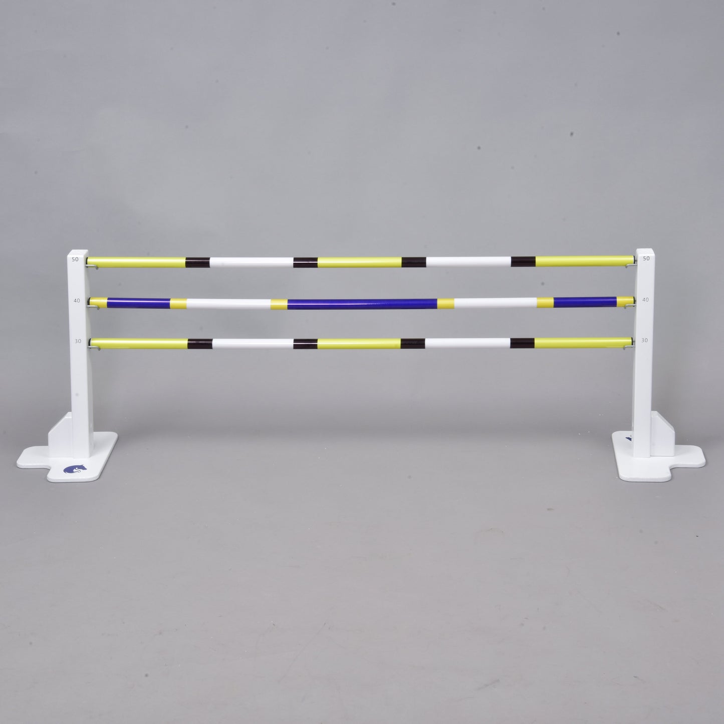 A white horse jumps the Hobby Horse LarDen Jump 50 cm / 20 inch with extra yellow, white, blue, and black poles against a gray background. Ideal for indoor or outdoor Hobby Horsing activities.